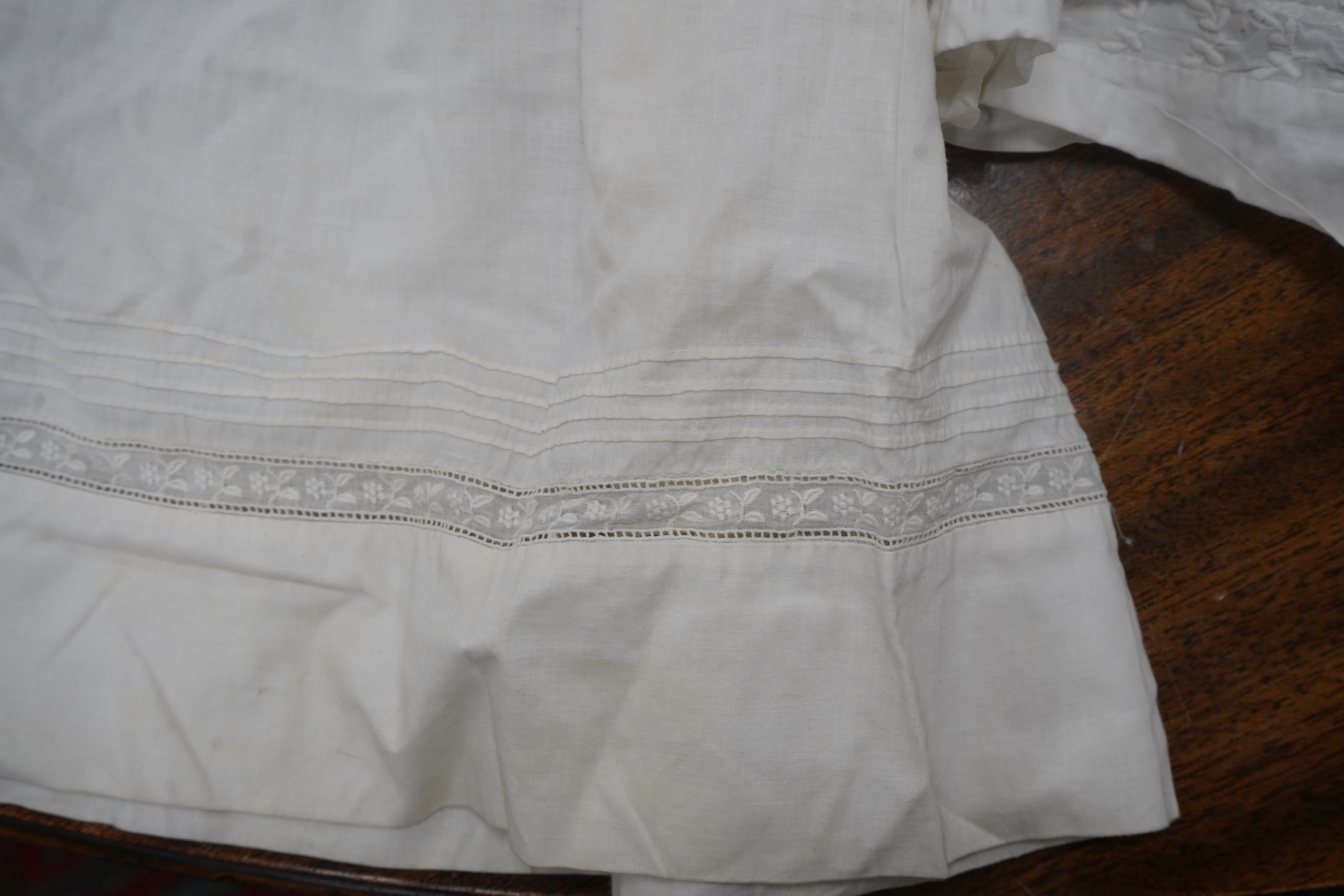 Two late 19th early 20th century long baby night gowns and two shorter baby gowns, together with a pink satin ladies full length slip and a similar cream silk stockinette slip, the bodices worked on baby dresses are embr